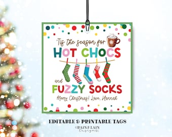 May include: A square Christmas gift tag with a green border and colorful polka dots. The tag reads "Tis the season for HOT CHOCS and FUZZY SOCKS." It features a hot chocolate illustration and hanging socks. Text at the bottom says "Merry Christmas! Love, Hannah."