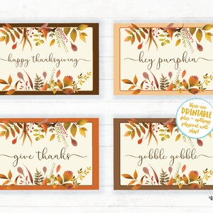 Op de afbeelding: Vier printbare kaarten met herfstbladeren en herfstthema tekst. De kaarten zeggen "happy thanksgiving", "hey pumpkin", "dankbaar zijn", en "kalkoen kalkoen".