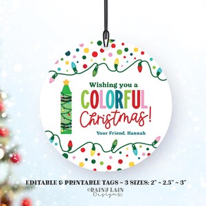 May include: A round, white Christmas ornament with a colorful design. It features a crayon-shaped Christmas tree with lights, confetti, and the text "Wishing you a COLORFUL Christmas! Your Friend, Hannah".
