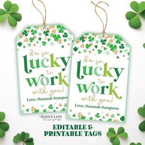 Puede incluir: Dos etiquetas de regalo blancas con detalles de tréboles verdes y dorados y el texto "I'm so lucky to work with you!" con una cuerda. Las etiquetas están rodeadas de tréboles verdes. Las palabras "Editable & Printable Tags" están en la parte inferior.