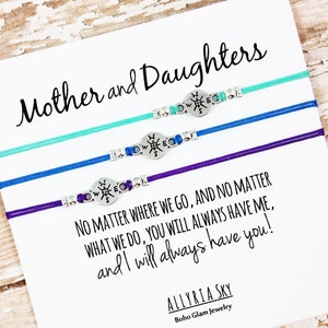 May include: A card with the text "Mother and Daughters" and a quote about always having each other, along with three bracelets with compass charms.