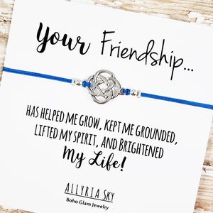 Puede incluir: Un brazalete de amistad azul con un dije de nudo celta plateado y una tarjeta que dice "Your Friendship... Has helped me grow, kept me grounded, lifted my spirit, and brightened my life!" Allyria Sky Boho Glam Jewelry