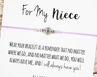 May include: A lavender cord bracelet with a silver compass charm and small silver beads. The card reads "For My Niece" and a message about always having each other. The brand name "ALLYRIA SKY" is at the bottom.