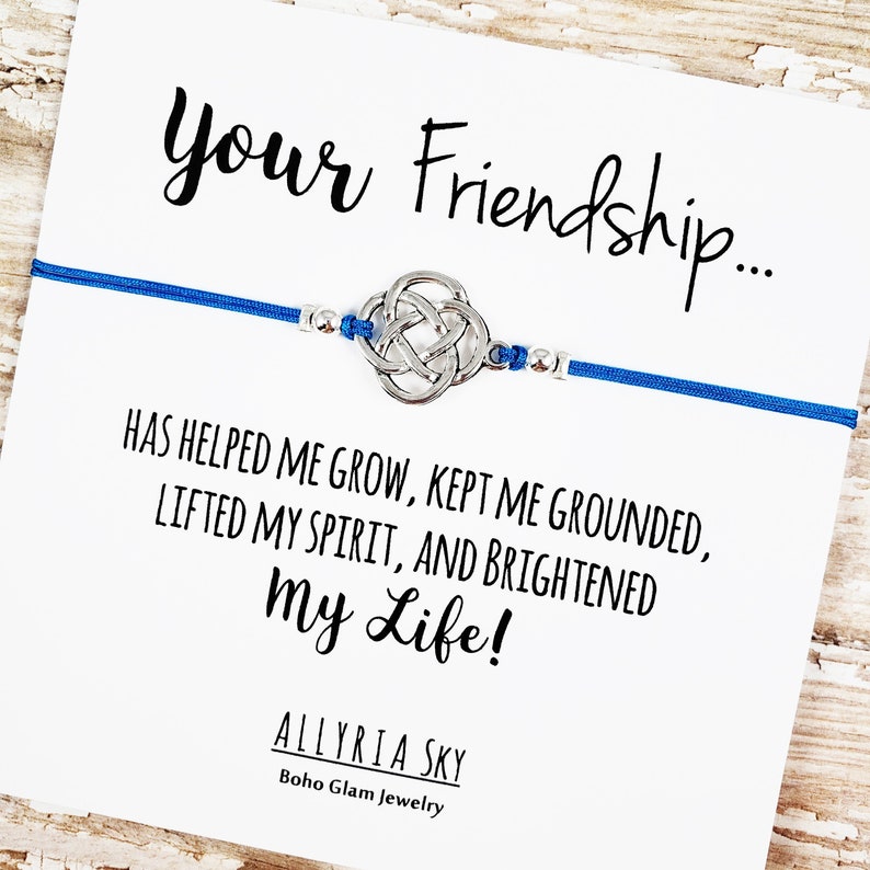 Puede incluir: Un brazalete de amistad azul con un dije de nudo celta plateado y una tarjeta que dice "Your Friendship... Has helped me grow, kept me grounded, lifted my spirit, and brightened my life!" Allyria Sky Boho Glam Jewelry