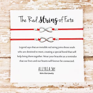 May include: Two red string bracelets with silver infinity charms. The card reads "The Red String of Fate" and includes a quote about the legend of the red string of fate. The card is signed "ALLYRIA SKY Boho Glam Jewelry".