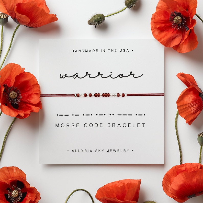 May include: Red and silver beaded bracelet with the word "warrior" written in cursive above it. The bracelet is displayed on a white card with the text "Morse Code Bracelet" and "Handmade in the USA" written below it.
