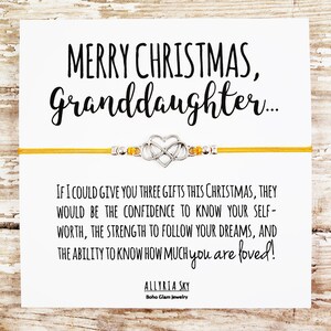 May include: A yellow string bracelet with a silver heart charm and the message "Merry Christmas, Granddaughter... If I could give you three gifts this Christmas, they would be the confidence to know your self-worth, the strength to follow your dreams, and the ability to know how much you are loved!"  Allyria Sky Boho Glam Jewelry