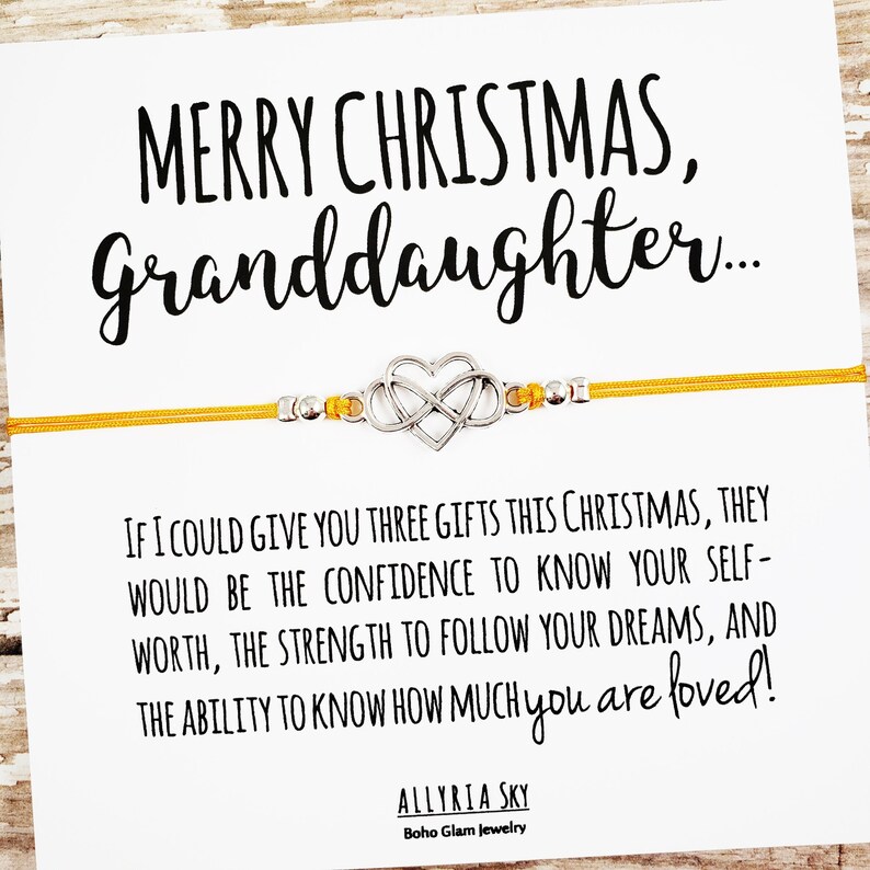 May include: A yellow string bracelet with a silver infinity heart charm. The bracelet has a message card attached that reads "Merry Christmas, Granddaughter... If I could give you three gifts this Christmas, they would be the confidence to know your self-worth, the strength to follow your dreams, and the ability to know how much you are loved!" The card is signed "Allyria Sky, Boho Glam Jewelry."