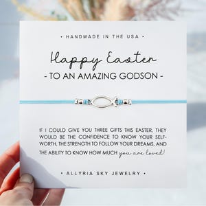 May include: A light blue string bracelet with a silver fish charm and beads. The bracelet comes with a card that says "Happy Easter to an amazing godson" and includes a message about the gifts of self-worth, strength, and love.