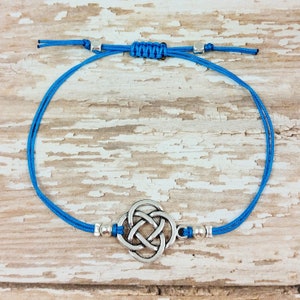 Puede incluir: Un brazalete de cord&oacute;n azul con un dije de nudo celta plateado y cuentas plateadas.