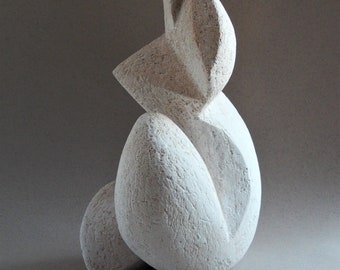Könnte beinhalten: Eine weiße Keramikskulptur mit abstraktem Design. Die Skulptur besteht aus geometrischen Formen und hat eine raue, strukturierte Oberfläche.