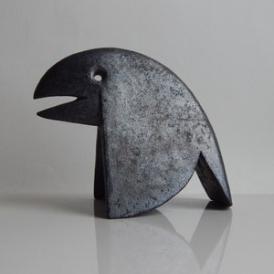 Könnte beinhalten: Eine schwarze Keramikskulptur eines Vogels mit einem stilisierten Schnabel und einer strukturierten Oberfläche.