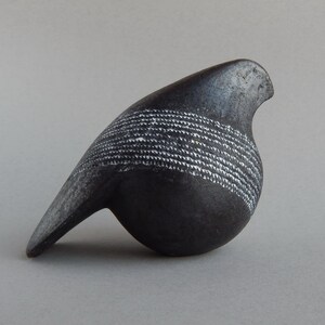 Puede incluir: Escultura de pájaro de cerámica negra con líneas blancas, cuerpo redondeado y pico largo.