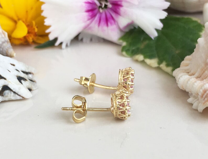 Puede incluir: Un par de pendientes de oro con piedras rosas engastadas en un dise&ntilde;o de corona.