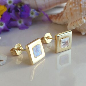 May include: A pair of gold square earrings with a clear moonstone in the center of each earring.