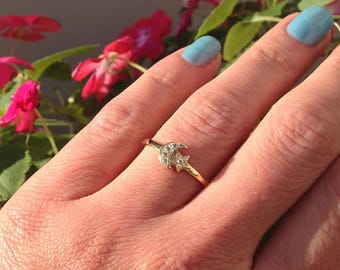 Puede incluir: Un anillo de oro con un diseño de luna creciente y estrella. El anillo está engastado con pequeñas piedras transparentes.