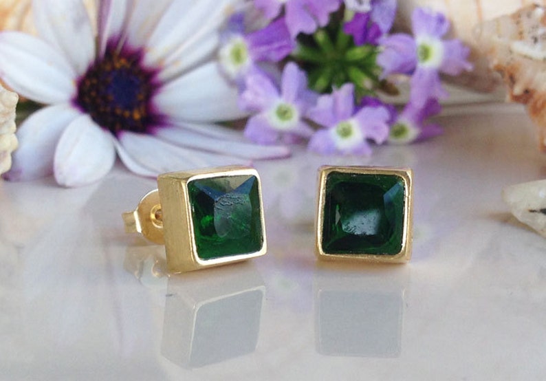 May include: A pair of gold square earrings with green gemstone accents.