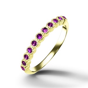 May include: A gold band ring with a row of purple gemstones. The ring has a delicate, ornate design.