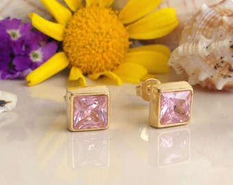 May include: A pair of gold square stud earrings with pink cubic zirconia stones.