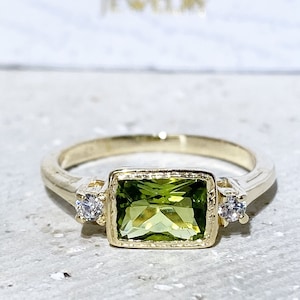 This gorgeous and elegant women's ring features an octagon-cut natural peridot gemstone with two round-cut dazzling clear quartz. This beautiful ring is enhanced with a high polish finish.