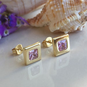 May include: A pair of gold square stud earrings with pink square gemstones.
