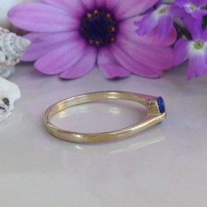 May include: A gold ring with a single blue gemstone set in the band.