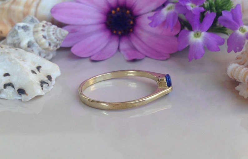 May include: A gold ring with a single blue gemstone set in the band.