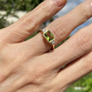 This gorgeous and elegant women's ring features an octagon-cut natural peridot gemstone with two round-cut dazzling clear quartz. This beautiful ring is enhanced with a high polish finish.