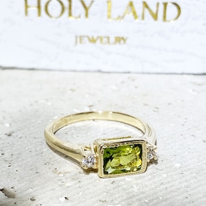 This gorgeous and elegant women's ring features an octagon-cut natural peridot gemstone with two round-cut dazzling clear quartz. This beautiful ring is enhanced with a high polish finish.