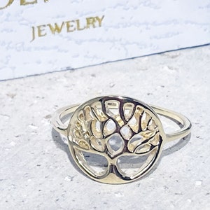 May include: A gold-toned ring featuring a tree of life design. The ring is crafted from metal and has a delicate, intricate design.