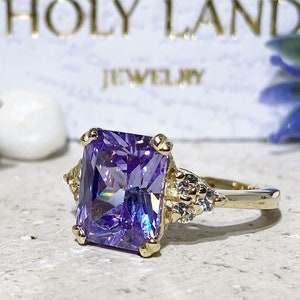 An absolute stunner, classic lavender amethyst engagement ring with an emerald cut gemstone of your choice as it’s centre stone and with round cut clear quartz on the band to further accentuate it.