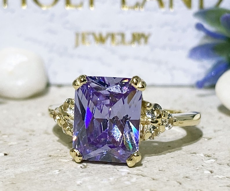 An absolute stunner, classic lavender amethyst engagement ring with an emerald cut gemstone of your choice as it’s centre stone and with round cut clear quartz on the band to further accentuate it.