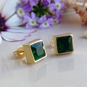 May include: A pair of gold square stud earrings with green gemstones.