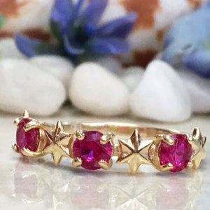 May include: A gold ring with five red gemstones and star-shaped accents.
