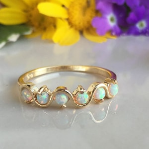 Può includere: Un anello a fascia d'oro con cinque pietre di opale bianco incastonate in un design ondulato.