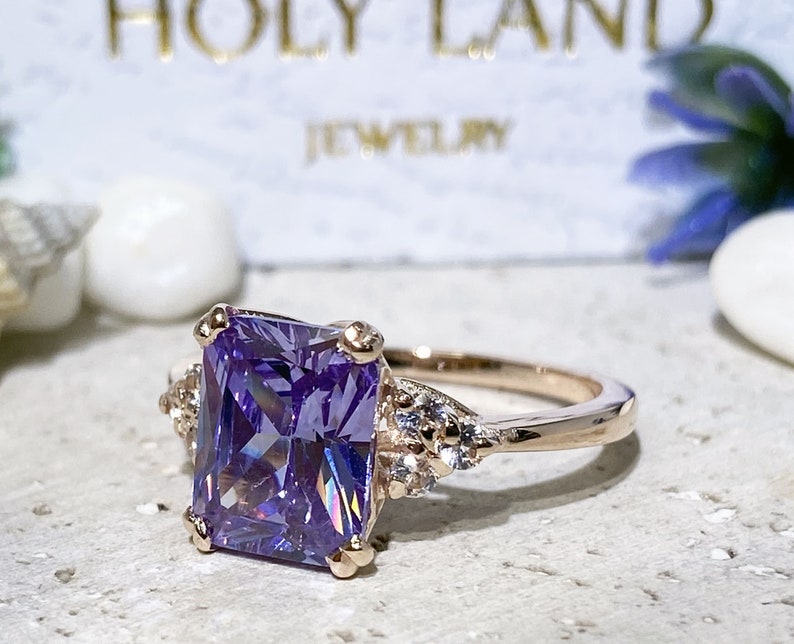 An absolute stunner, classic lavender amethyst engagement ring with an emerald cut gemstone of your choice as it’s centre stone and with round cut clear quartz on the band to further accentuate it.