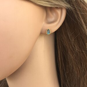Puede incluir: Un par de pendientes de bot&oacute;n de oro con una piedra preciosa azul en forma de l&aacute;grima engastada en un engaste de oro.
