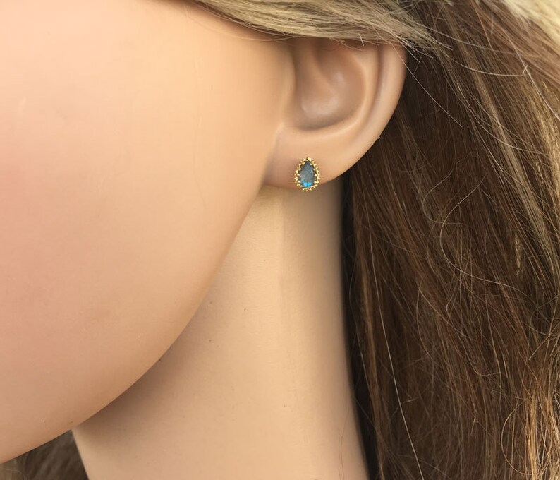Puede incluir: Un par de pendientes de bot&oacute;n de oro con una piedra preciosa azul en forma de l&aacute;grima engastada en un engaste de oro.