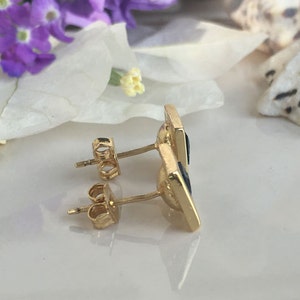 May include: A pair of gold earrings with black square-shaped stones. The earrings have a post and butterfly back.