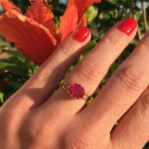 May include: A gold ring with a red gemstone set in a crown-like setting.