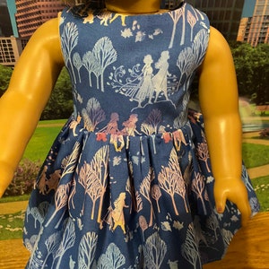May include: A blue sleeveless dress with a white and purple floral pattern featuring silhouettes of characters from the film Frozen. The dress has a gathered skirt and a scoop neckline.