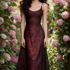 May include: A formal gown with a burgundy bodice and a black lace overlay. The dress features a spaghetti strap neckline and a flowing skirt. The gown is adorned with small, dark embellishments and is suitable for special occasions.