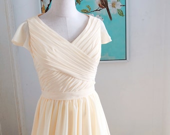 May include: A pale yellow, sleeveless dress with a V-neckline and a pleated bodice. The dress has a fitted waist and a flowing skirt.