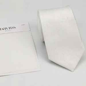 Puede incluir: Una corbata blanca con un sutil estampado de cachemira, junto a una muestra de tela blanca. La muestra de tela tiene el texto "DAVID'S BRIDAL" impreso. La corbata está doblada.
