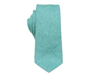 Puede incluir: Una corbata de color verde azulado con estampado. La corbata está hecha de un tejido texturizado.