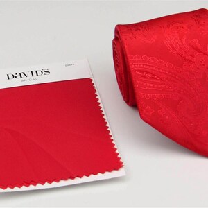 Puede incluir: Una muestra de tela roja etiquetada como "Scarlet" y una corbata roja con estampado paisley. La muestra de tela es de David's Bridal.