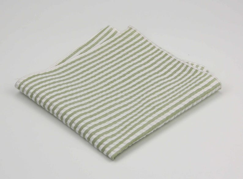 May include: A white and green striped linen pocket square. The pocket square is folded in half and has a subtle texture.