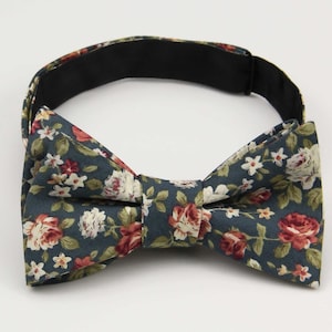 Puede incluir: Una pajarita azul oscuro con un estampado floral con flores rojas, blancas y verdes.