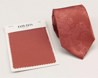 Può includere: Un campionario di tessuti con il testo "David's Bridal" e il colore "Sedona" visualizzato. Una cravatta abbinata con un motivo paisley è mostrata accanto al campionario.