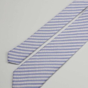 May include: A blue and white striped tie. The tie is made of a soft, textured fabric.